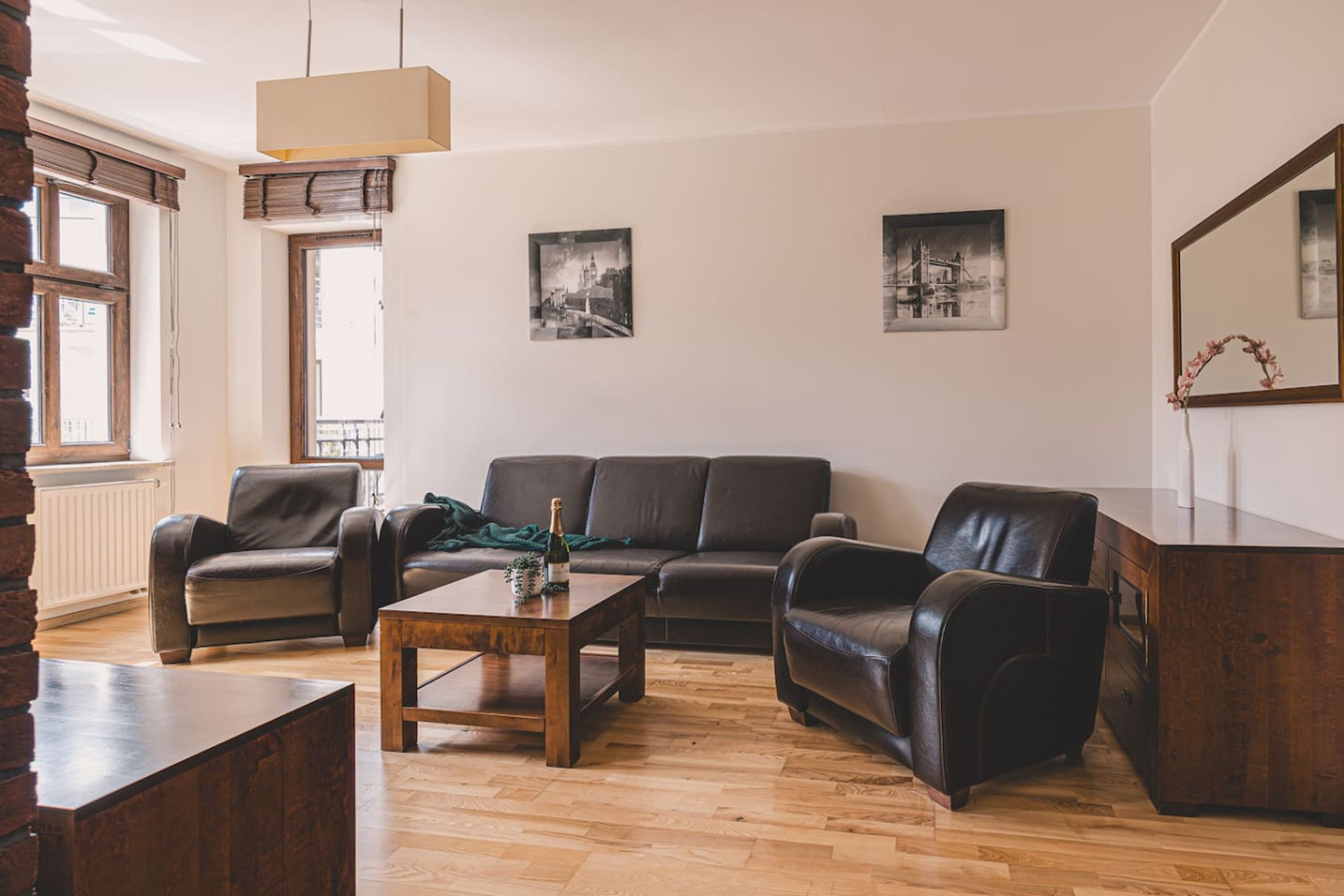 A living room with a wooden coffee table, leather sofas, and a large mirror.