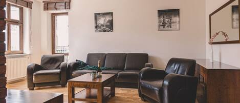 A living room with a wooden coffee table, leather sofas, and a large mirror.