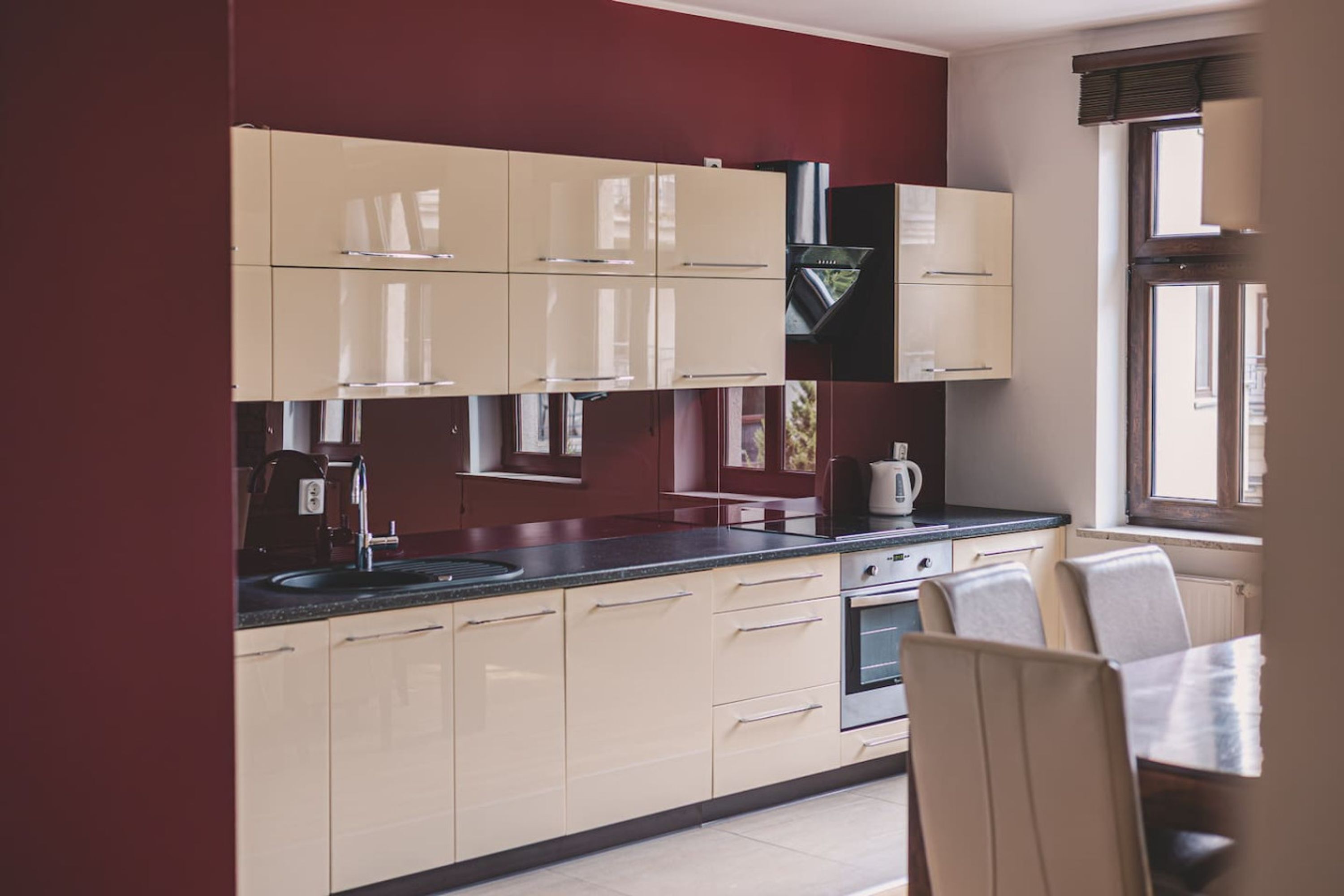 A modern kitchen with beige cabinets, a black countertop, and a window providing natural light.