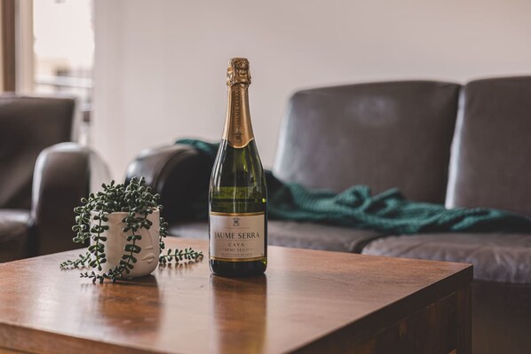 Une bouteille de vin mousseux Jaume Serra est posée sur une table en bois, à côté d’une plante en pot.
