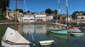 A harbor with several boats docked, a stone wall, and buildings in the background.
