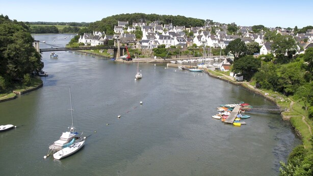 A river with boats and a bridge. There are houses along the riverbank.