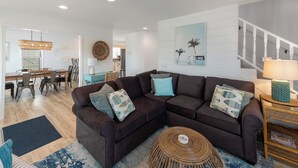 Una sala de estar moderna con un sofá modular, un comedor y una escalera.