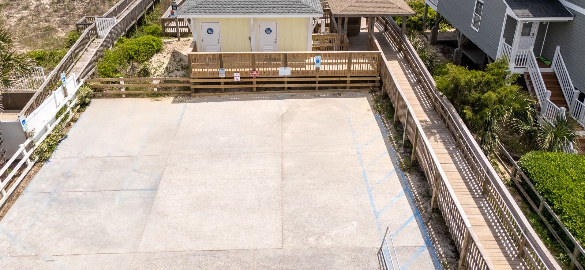 Une propriété située en bord de mer, dotée d’une grande terrasse en béton, d’une plateforme en bois et d’un petit bâtiment avec deux portes.