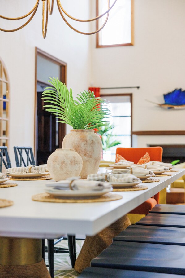 A dining table set with plates, a vase with a plant, and chairs.