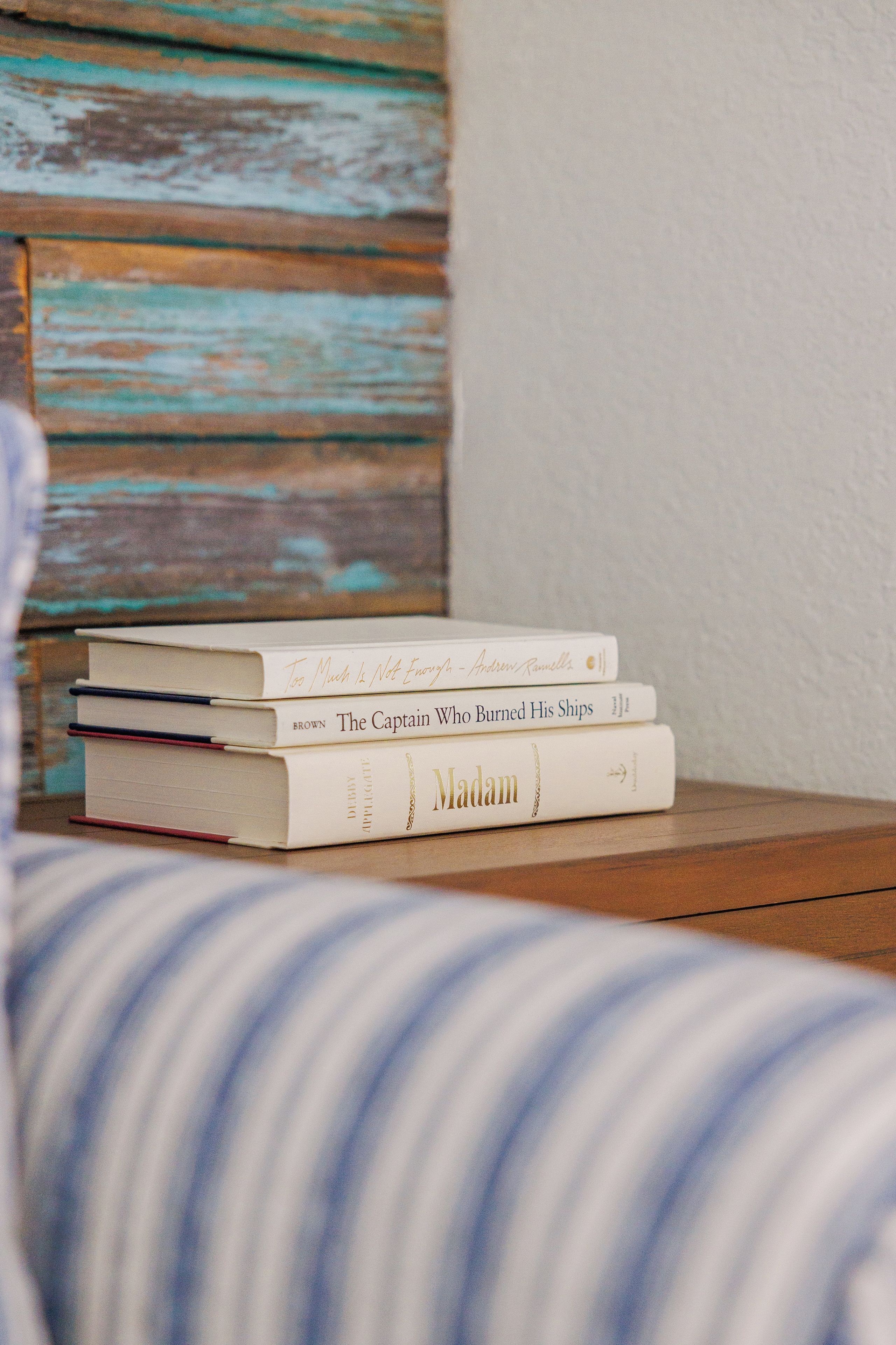 A stack of books on a wooden nightstand.