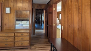 Un couloir en bois avec un lit, une commode et une table.