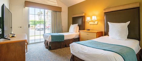 Une chambre d’hôtel avec deux lits, un bureau, une télévision et une vue sur l’extérieur.