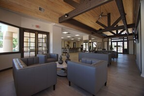 A spacious lobby with high ceilings, exposed beams, and a seating area with sofas and a coffee table.