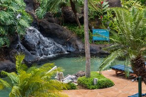 A waterfall, a pool, and a bench in a tropical garden setting. - Studio w/ Balcony & Full Kitchen | Access to Pool (Lahaina)