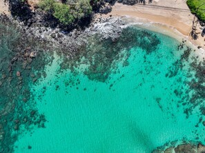 An aerial view of a beach with clear turquoise water, rocky shoreline, and dense greenery. - Studio w/ Balcony & Full Kitchen | Access to Pool (Lahaina)