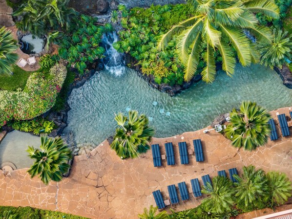 A resort with a clear pool, palm trees, and a waterfall. - Studio w/ Balcony & Full Kitchen | Access to Pool (Lahaina)