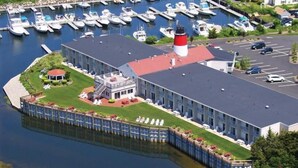 A marina with boats docked, a building with a red roof, and a lighthouse. - 1BR Condo w/ Kitchenette & Balcony | Pools Access (South Yarmouth)