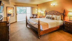 Een hotelkamer met een groot bed, een dressoir, een stoel en een raam met gordijnen.