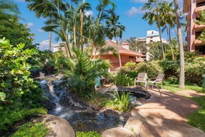 A tropical resort with a waterfall, lush greenery, and a pool area with lounge chairs. - Cozy Studio Hotel Stay w/ Resort Amenities (Lahaina)