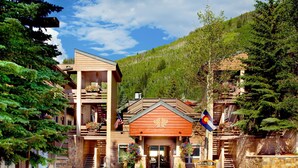 A lodge with a wooden facade, a flag, and a mountain backdrop. - Cozy 1BR Condo w/ Pool Access in Vail (Vail)