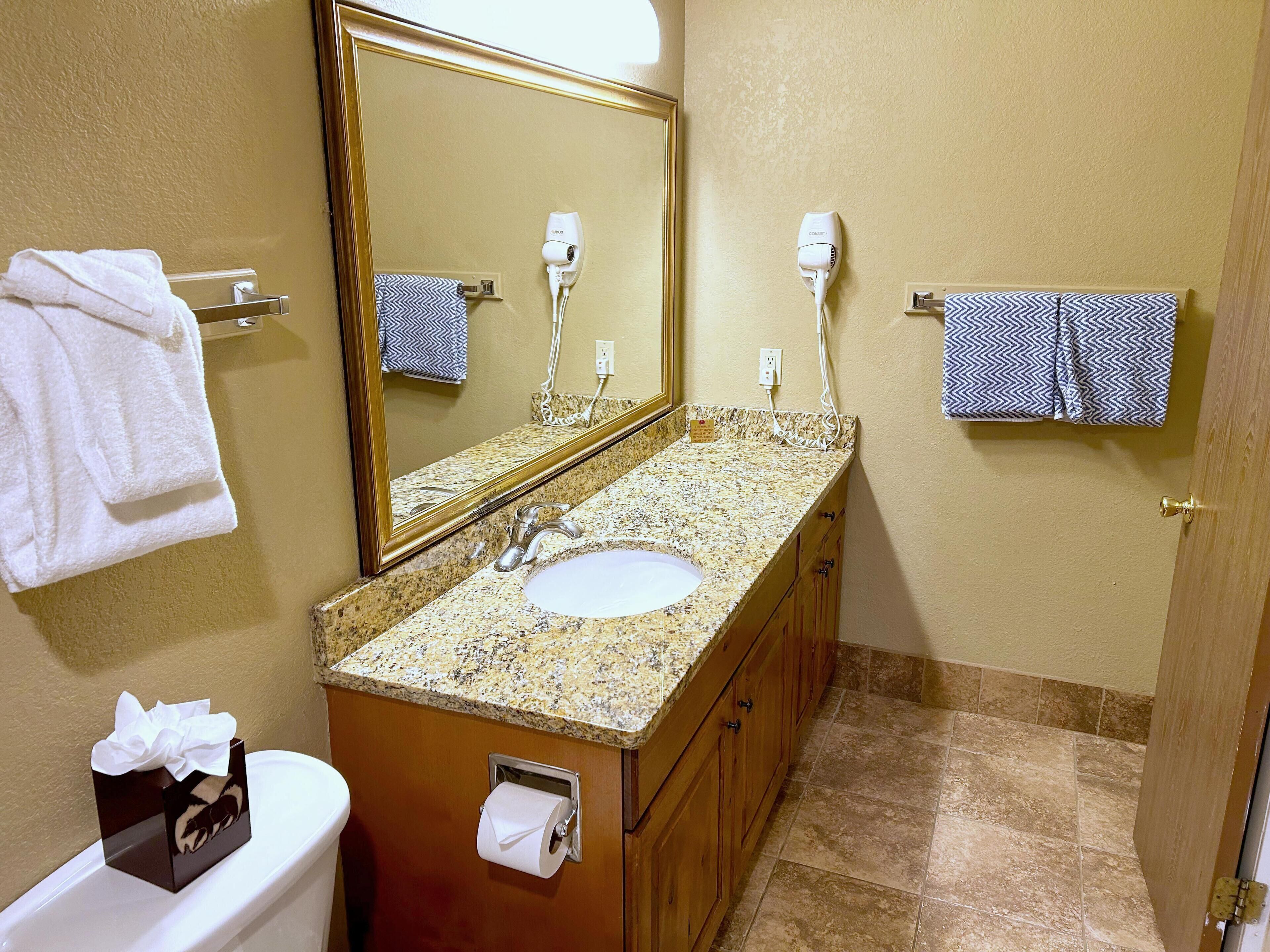 Ein Badezimmer mit Waschbecken, Spiegel, Handtuchhalter und Toilette.
