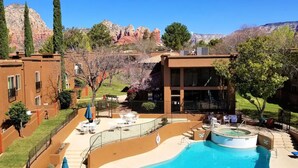 A hotel with a pool area, outdoor seating, and a view of red rock formations.