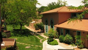 A residential area with a house featuring a tiled roof, arched windows, and a well-maintained lawn.