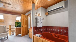 Une salle de bain avec une baignoire en bois, une douche et un meuble-lavabo en bois. On y trouve également un ventilateur de plafond et un appareil de climatisation.