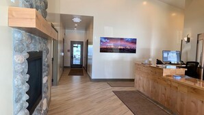 A reception area with a stone wall, wooden reception desk, and a monitor.
