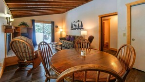 A dining area with a wooden table and chairs, a sofa, and a wall with a mountain and deer mural.