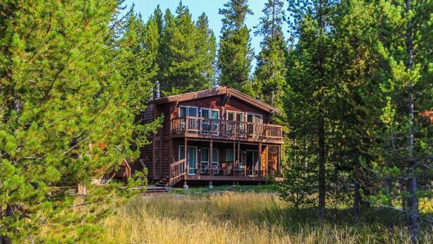 A cabin with a wooden exterior, a balcony, and a deck.
