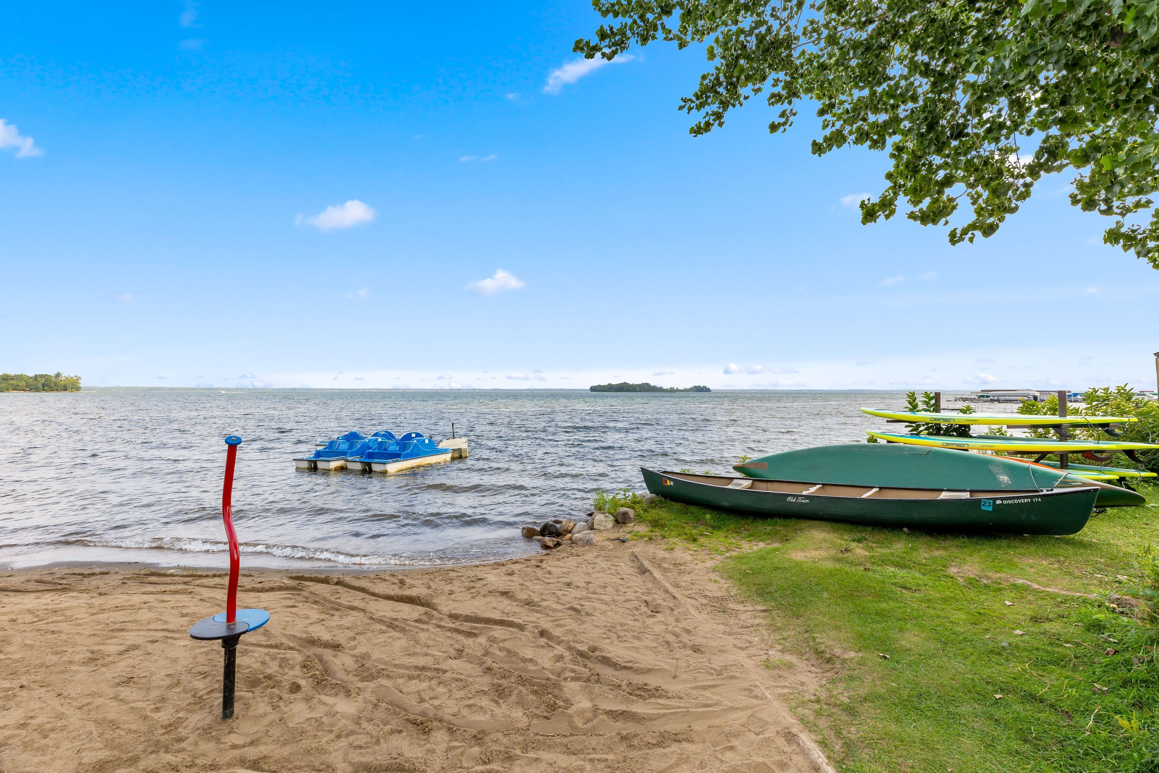 Een zandstrand met boten en een rode paal.