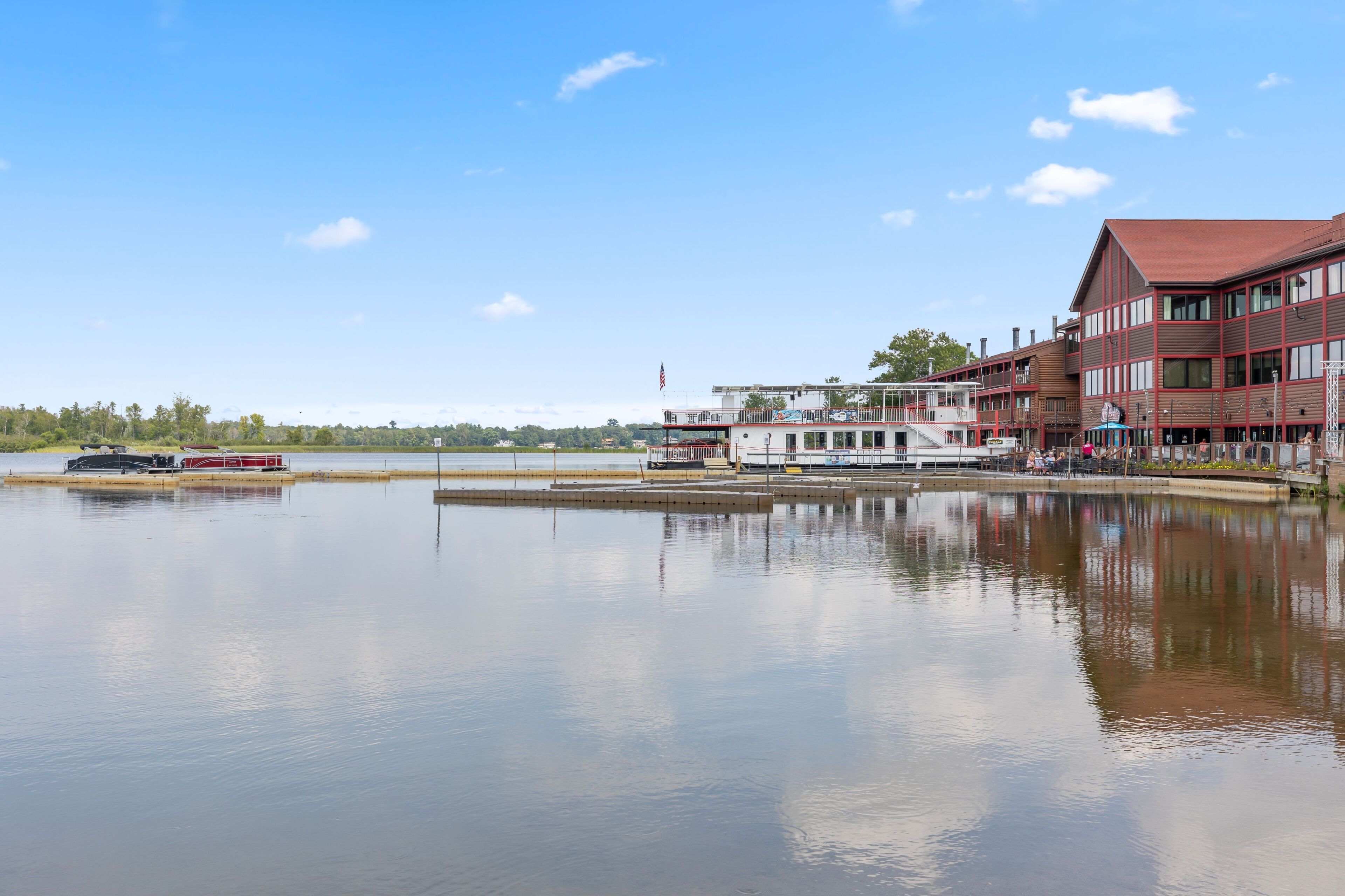 Ein Hotel am Ufer mit einem großen Gebäude, einer Anlegestelle und einem ruhigen See.