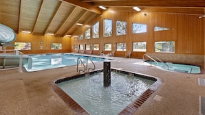 An indoor swimming pool with multiple lanes, a hot tub, and wooden walls with large windows. - Point Condos 2BR w/ Lake Views & Fireplace (Breezy Point)