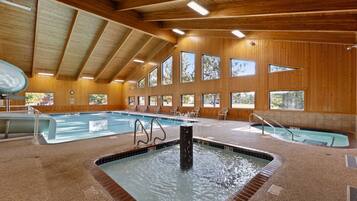 Une piscine intérieure dotée de plusieurs couloirs, d’un jacuzzi et de murs en bois avec de grandes fenêtres.
