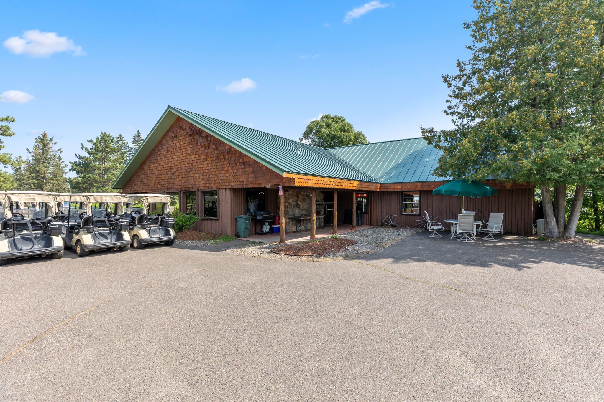 Een lodge met een overdekte veranda, een eethoek en een parkeerplaats met golfkarretjes.