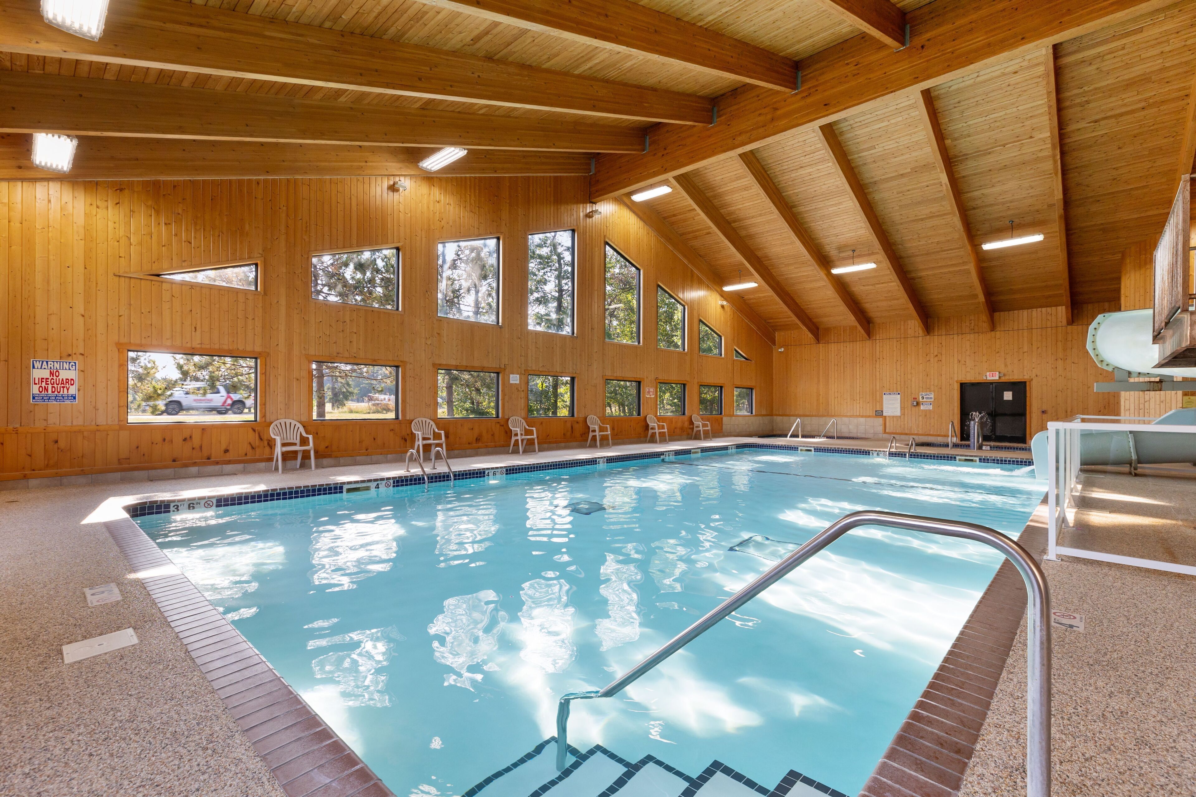 An indoor swimming pool with wooden walls and large windows.