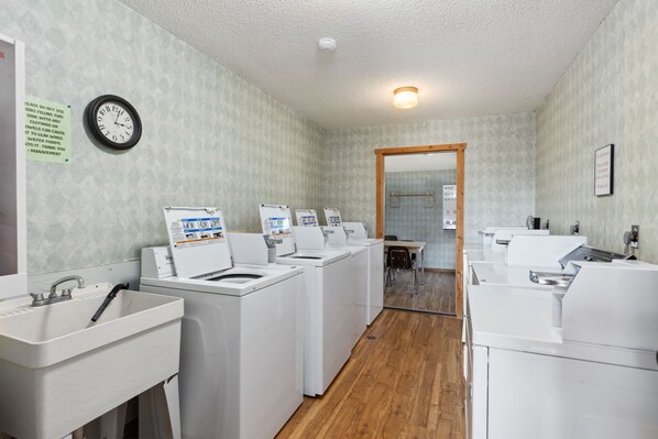 A laundry room with multiple washing machines and a sink.