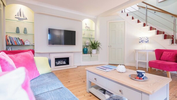 Ein modernes Wohnzimmer mit Flachbildfernseher, Kamin, Treppe und Bücherregal.