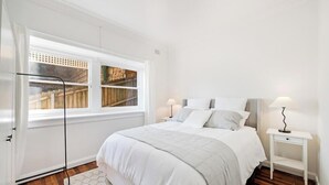 A bedroom with a bed, nightstands, a window, and a door.