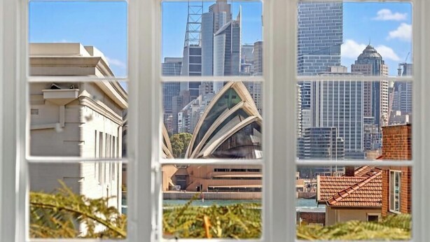 A view through a window of a cityscape with modern buildings, including a distinctive curved structure.