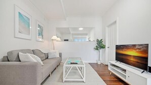 A modern living room with a sofa, coffee table, TV, and framed pictures on the wall.