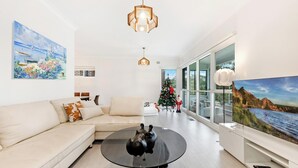 A modern living room with a sofa, a coffee table, a Christmas tree, and a large window with a scenic view.