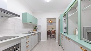 A modern kitchen with white cabinets, a built-in oven, and a dining area with a table and chairs.