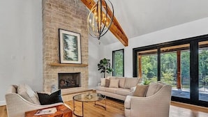 A spacious living room with a brick fireplace, a modern chandelier, a sofa, and a coffee table. - Private Dock, 30 day rentals (Union Hall)