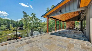 A modern outdoor patio with stone flooring, a wooden ceiling, and a brick fireplace. - Private Dock, 30 day rentals (Union Hall)