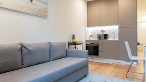 A modern living room with a grey sofa, a small table with a pineapple, and a painting on the wall. - Cozy & Bright Flat by Host Wise (Guimarães)