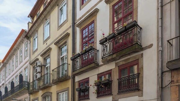 A building with a sign reading "QUATTRO." balconies with wrought iron railings and a red awning. - Luxurious Decor Studio | Clérigos by HostWise (Porto)