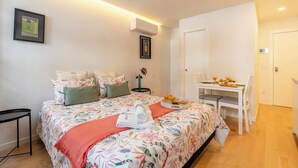 A bedroom with a bed, bedside table, and a desk with chairs. - Luxurious Decor Studio | Clérigos by HostWise (Porto)