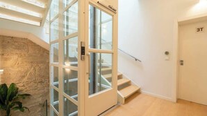A modern interior with a glass door leading to a staircase, a stone wall, and a door labeled "3T". - Luxurious Decor Studio | Clérigos by HostWise (Porto)