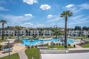 Ein Resort mit einem großen Schwimmbecken, umgeben von Liegestühlen und Palmen.