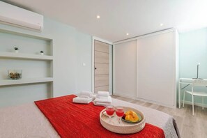 A modern hotel room with a bed, a red throw, towels, a breakfast tray, and a desk with a chair. - HostWise - Quinta do Vintém near WOW (Vila Nova de Gaia)