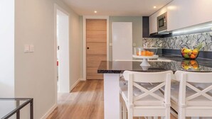 A modern kitchen with a central island, white chairs, and a microwave above the counter.