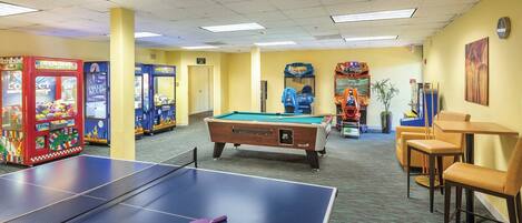 A recreational area with a pool table, arcade games, and a billiards table.